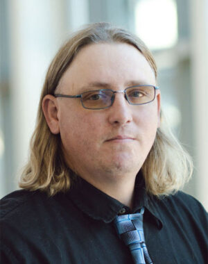 a man with long hair wearing glasses and a black shirt