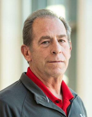 a man with grey hair wearing a red collared shirt