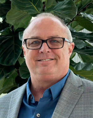 a man wearing glasses and a grey suit